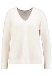 Jersey blanco de punto con escote en V, mangas largas y patrón texturizado. Presenta puños de canalé y un pequeño acento metálico en el dobladillo.