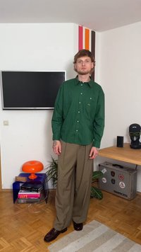 Grün gestreifte Hemdbluse mit entspannter Passform, kombiniert mit beigen weitgeschnittenen Hosen und dunkelbraunen Schuhen. Modernes und lässiges Design.