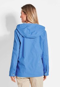 Helleblaue wasserdichte Jacke mit Kapuze, ausgestattet mit langen Ärmeln und Druckknopfmanschetten. Glatte Textur und minimalistisches Design.