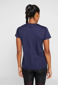 Maglietta sportiva blu navy con maniche corte, scollo rotondo e tessuto strutturato. Presenta una cucitura centrale e arricciature laterali per garantire comfort.