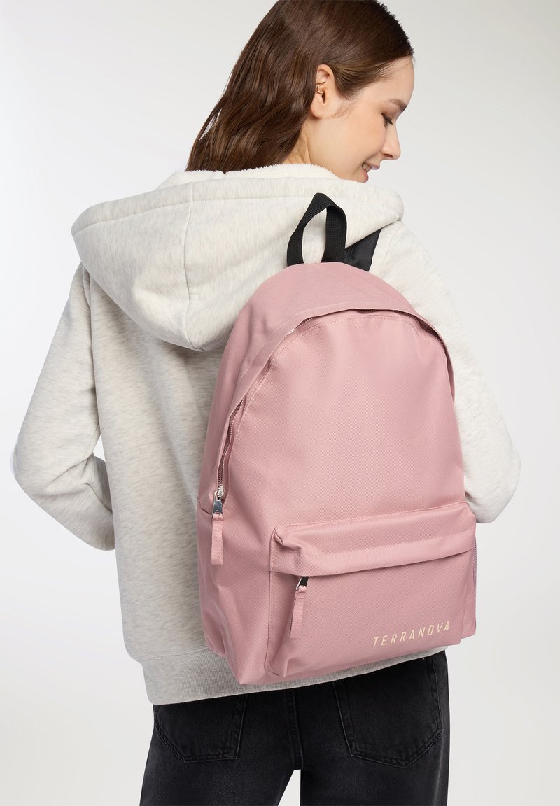 Zaino rosa chiaro realizzato in tessuto con una texture liscia, dotato di tasca anteriore con zip e logo dorato "TERRANOVA". Cinghie nere attaccate.