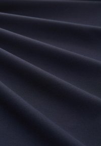 Tissu bleu marine foncé avec une texture douce et lisse présenté en plis délicats mettant en valeur la qualité du matériau.
