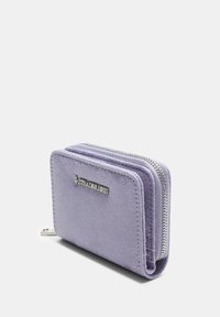Portafoglio in suede viola con chiusura a zip, dotato di un logo argentato sulla parte anteriore e un design compatto e rettangolare.