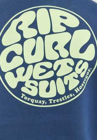 Il tessuto blu presenta un logo circolare con un grande testo verde chiaro che recita "RIP CURL WETSUITS" e "Torquay, Trestles, Hossegor."