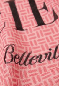 Pink tekstil med et struktureret mønster af sammenlåsende rektangler, med ordene "Belleville" og "LIE" i fed sort skrift.