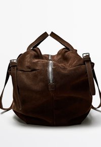 Brun mockaklädd duffelväska med silverfärgad dragkedja, dubbla övre handtag och avtagbar axelrem; mjuk textur, rundad form.