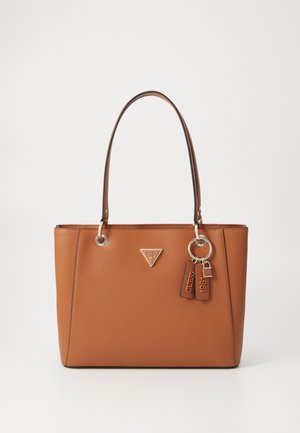 Sac fourre-tout synthétique beige avec doubles poignées, ferrures argentées, badge logo et accents de porte-clés. Fini texturé avec une forme structurée.