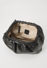 Borsa a mano in pelle nera con design arricciato, dotata di un interno beige con un motivo a spina di pesce e una tasca con zip.
