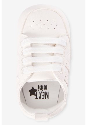 White baby sneaker with perforated toe, white laces, and "NEXT mini" logo inside sole.