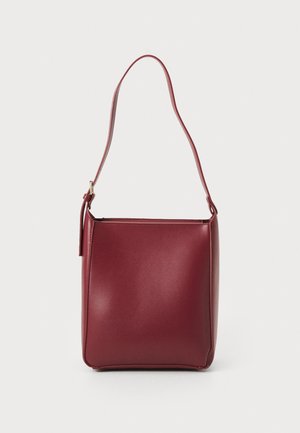 Burgundy syntetisk handväska med en enda axelrem, fyrkantig form, slät yta och minimalistisk design. Guldiga detaljer.