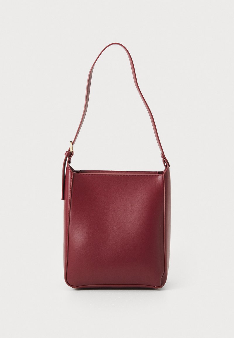 Burgundy synthetic handbag with a single shoulder strap, square shape, smooth texture, and minimalistic design. Gold hardware accents.