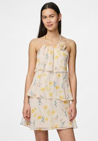 Blommig halterneckklänning i genomskinligt lätt tyg med en lagerdesign. Har gula och blå blommor samt en dekorativ tygblomma som accent.