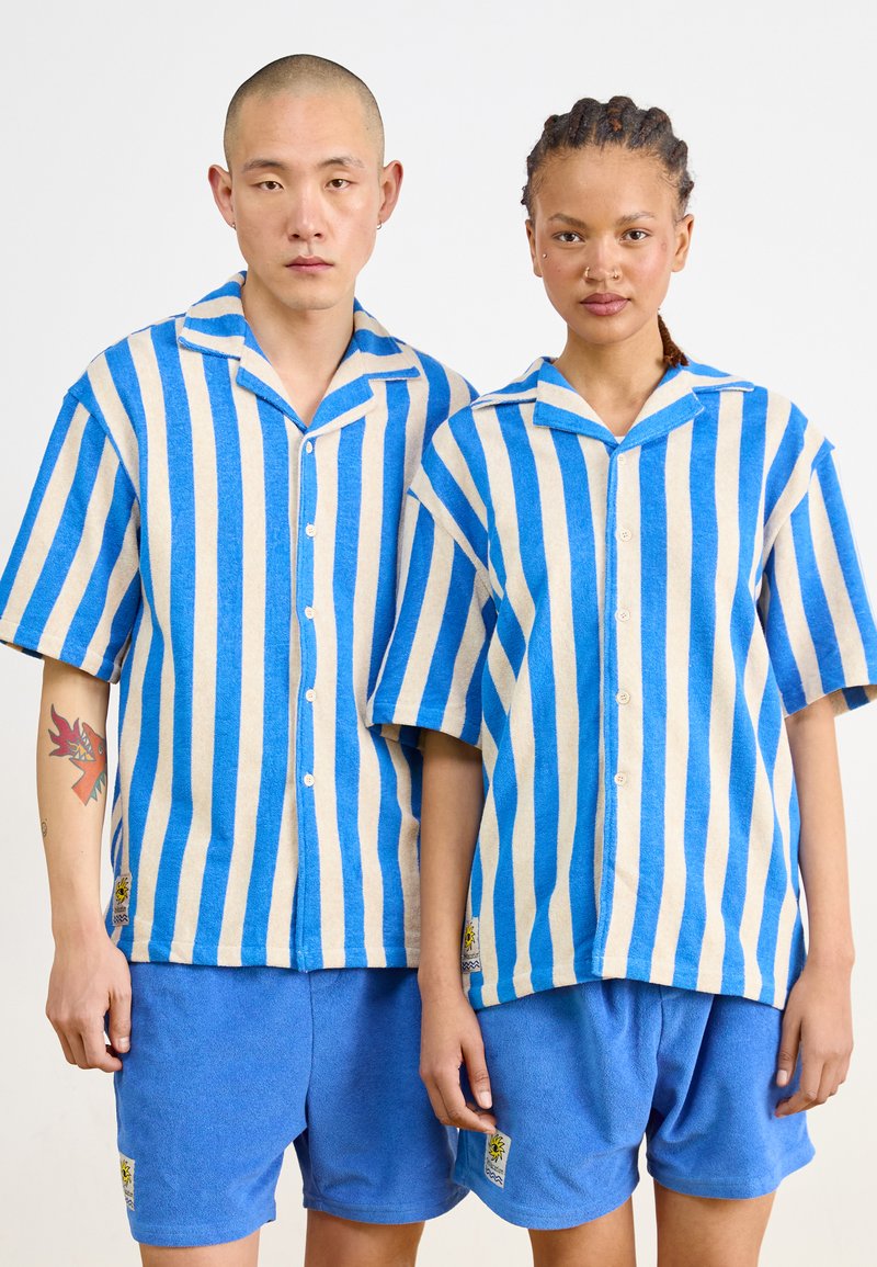 Ontspannen pasvorm, hemden met korte mouwen in blauw en beige verticale strepen, gecombineerd met effen blauwe shorts. Textuurstof met knopen aan de voorkant.