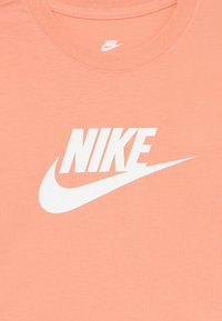 Gaiši persiku krāsas kokvilnas T-krekls ar lielu baltu Nike logotipu un swoosh dizainu. Apaļa kakla izgriezums un īsas piedurknes. Gluda tekstūra.