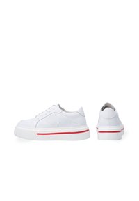 White leather sneakers with perforated sides, rubber soles, and a red accent stripe. Rounded design with lace closure. Back view included.