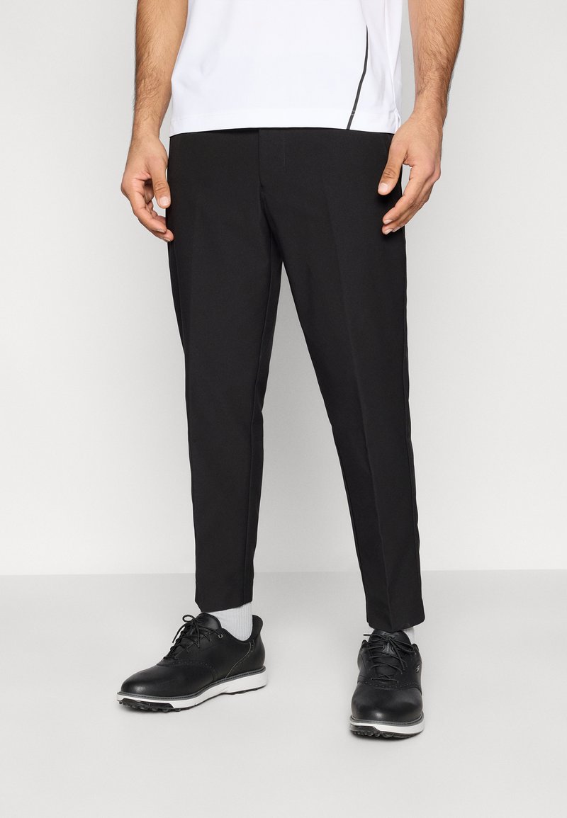 Μαύρο παντελόνι κομμένο στα μέτρα με στενή εφαρμογή, λεία υφή και πλαϊνές τσέπες, σε συνδυασμό με μαύρα παπούτσια με κορδόνια και γκρι κάλτσες.