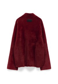 Giacca in pelliccia sintetica bordeaux con una texture morbida, maniche lunghe e un fit rilassato. Presenta un'etichetta nera rettangolare sul retro.
