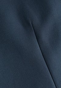 Tejido texturizado de color azul marino con una costura diagonal, que muestra una superficie suave y tejida creando un patrón sutil. Material duradero con un acabado mate.