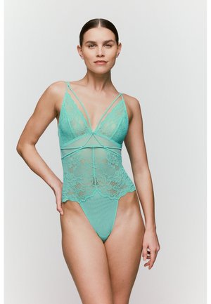 Mintgrüner Spitzen-Body mit einem transparenten Mesh-Überzug, verstellbaren Trägern, floralen Mustern und einem Tanga-Schnitt am Boden.