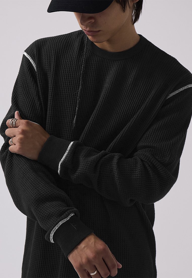 Schwarzes Waffelstrick-langarmshirt mit gerippten Bündchen, versehen mit feinen weißen Akzentnähten an den Schultern und einem lässigen Schnitt.