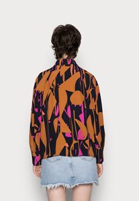 Kortærmet skjorte med et levende abstrakt mønster i orange, pink og sort. Har en klassisk krave og afslappet pasform.