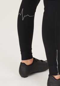 Zwarte sportleggingen met een grafische hartslaglijn in het grijs aan de linkerkant, voorzien van een eenritsmanchet en een soepele, rekbare stof.
