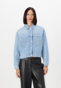 Giacca cropped in denim azzurro con chiusura a bottoni, due tasche sul petto e colletto classico. Maniche lunghe e texture leggermente vissuta.