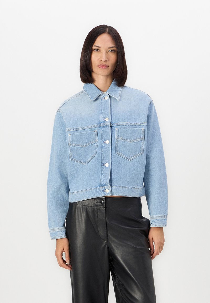 Giacca cropped in denim azzurro con chiusura a bottoni, due tasche sul petto e colletto classico. Maniche lunghe e texture leggermente vissuta.