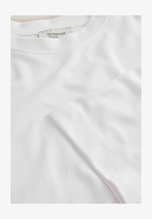 Valkoinen puuvillainen T-paita, jossa pyöreä pääntie ja lyhyet hihat. Ominaisuuksiin kuuluu sileä pinta ja siistit saumat reunoilla.