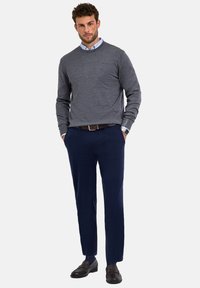 Maglione grigio in maglia testurizzata, abbinato a pantaloni navy sartoriali. Cintura in pelle marrone e scarpe coordinate completano l'outfit.
