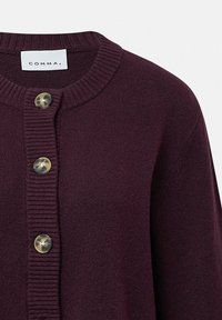 Donker pruimenkaartigan gemaakt van zachte breimateriaal. Beschikt over een geribbelde kraag, een getextureerde knopenlijst en twee ronde knopen met een subtiele glans.