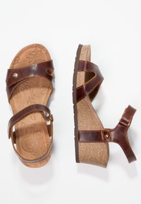 Sandalias de cuña de cuero marrón con plantillas de diseño floral, correas ajustables y suela de corcho texturizado, que cuentan con un acento decorativo de metal.