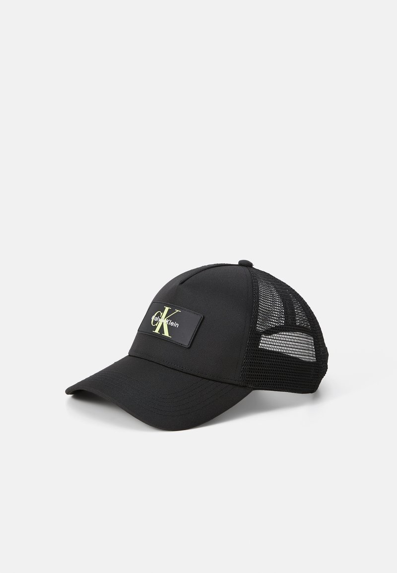Sort kasket med mesh bagpå, med et rektangulært logo patch i sort og gul. Buet skygge og struktureret design for et tætsiddende look.