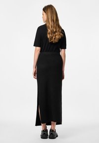 Črna rebrasta krilo s stranskim razporkom, v kombinaciji s črnim kratkimen sleeves topom in črnimi supergami. Gladka tekstura in oprijet kroj.