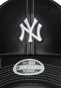 Zwarte leren pet met een witte geborduurde New York Yankees-logo, met contrasterende witte stiksels en een verstelbare strap label.