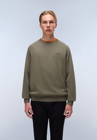 Olijfgroene sweater met raglanmouwen, geribbelde manchetten en zoom. Heeft een klein logo op de borst en een oranje binnenste halslijn.