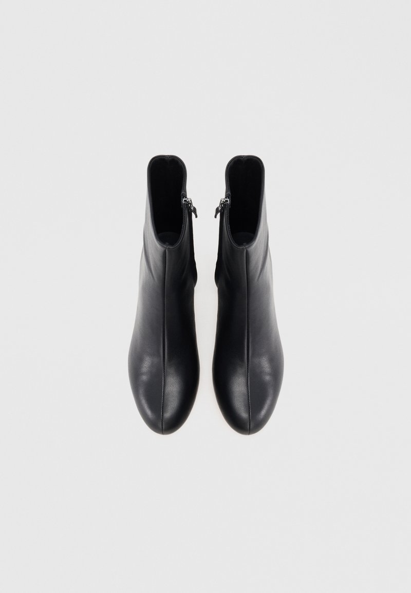 Stivali in pelle nera alla caviglia con una texture liscia, punta tonda e doppie chiusure con zip su ciascun lato, caratterizzati da una silhouette snella.