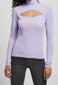 Fialový top s dlouhým rukávem a stojáčkem, který má výřez na hrudi. Vyrobeno z hladké, elastické tkaniny. V kombinaci s tmavými džíny.