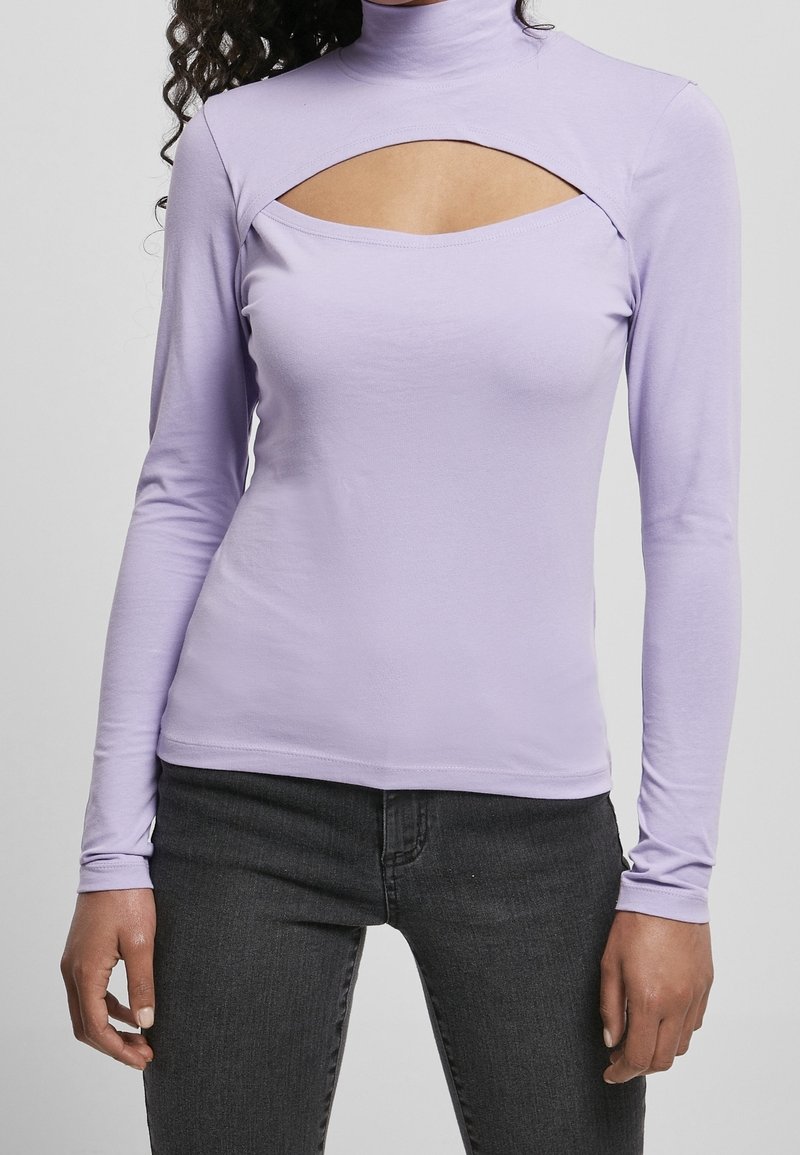 Fialový top s dlouhým rukávem a stojáčkem, který má výřez na hrudi. Vyrobeno z hladké, elastické tkaniny. V kombinaci s tmavými džíny.