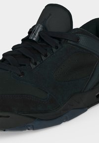 Κοντινό πλάνο μαύρου αθλητικού παπουτσιού με ψηλό πέλμα, επένδυση στον αστράγαλο, κορδόνια μπροστά και υφή στη σόλα σχεδιασμένη για αθλητική χρήση.