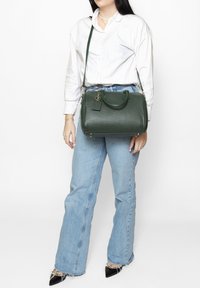 Borsa a mano in pelle verde con forma strutturata, manici superiori e tracolla staccabile. Presenta hardware dorato e superficie texturizzata.