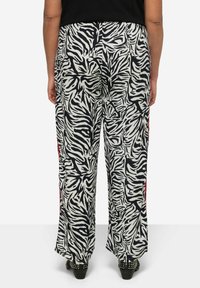 Zwart-witte zebraprint wijde broek met rode zijstrepen, gemaakt van lichtgewicht stof, met een relaxte pasvorm en een lange binnenbeenlengte.