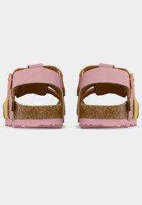 Ζευγάρι ροζ και κίτρινων σανδαλιών με ρυθμιζόμενα λουράκια και φάσες φελλού, φωτογραφημένα από πίσω σε λευκό φόντο.