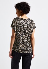 Top a maniche corte con stampa leopardata in beige e nero, caratterizzato da una vestibilità morbida e scollo rotondo. Tessuto morbido con una sottile texture.