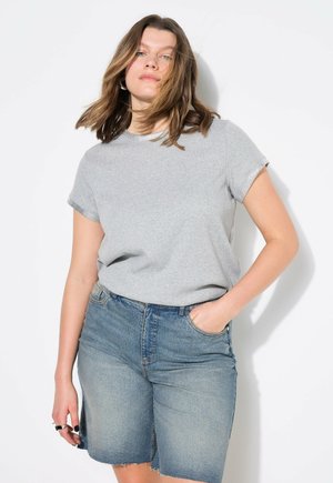 Graues T-Shirt mit kurzen Ärmeln und rundem Halsausschnitt, kombiniert mit verblassten Jeansshorts. Das T-Shirt hat einen dezenten strukturierten Besatz am Halsausschnitt.