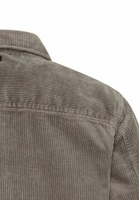 Grå fløjlsbluse med lodret ribbet tekstur, en klassisk krave og synlige sømme langs skuldersømmen.