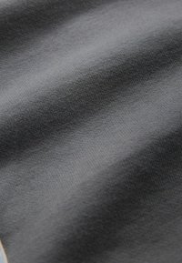 Harmaa kangas, jossa on pehmeä, tekstuuri pinta ja hienovaraiset vaakaraitat. Materiaali on todennäköisesti puuvillaa tai puuvillasekoitetta.