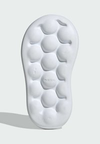 White rubber shoe sole featuring a bubble-like pattern with embossed branding. Smooth texture with rounded protrusions and a curved outline.