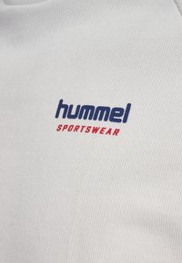 hummel sportkleding logo in blauw en rood op witte textuurstof