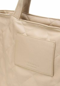 Borsa tote in pelle beige trapuntata con tasca piatta, logo in rilievo e manici robusti. Texture liscia con motivo a diamante.